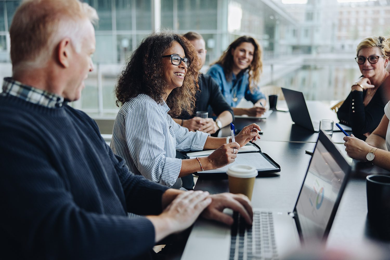 A group of smiling people sitting around a conference desk.