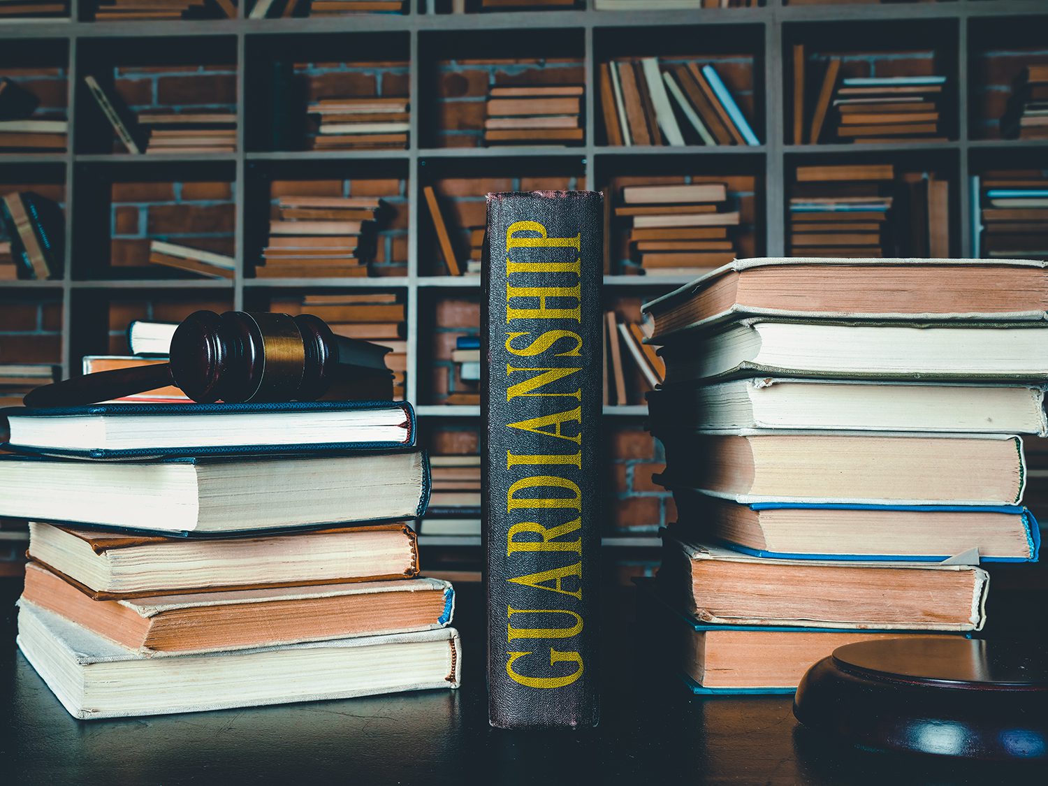 A black book with a spine that says “guardianship” in yellow between two stacks of books.